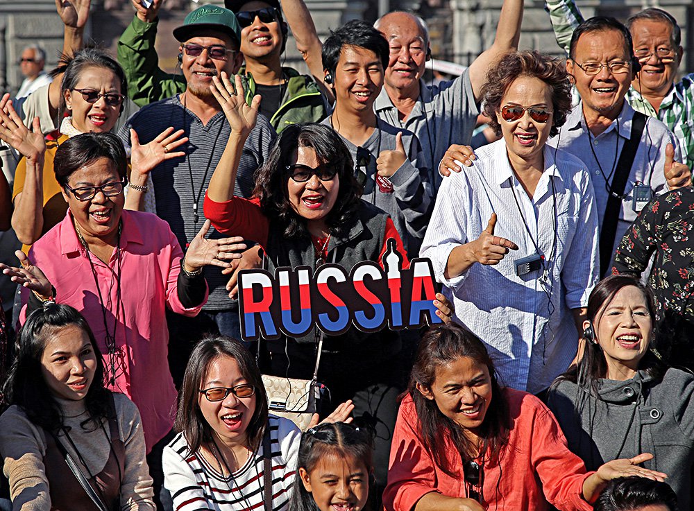 Туристы позируют фотографу на Дворцовой площади в Санкт-Петербурге. Фото: Павел Каравашкин/ Коммерсантъ