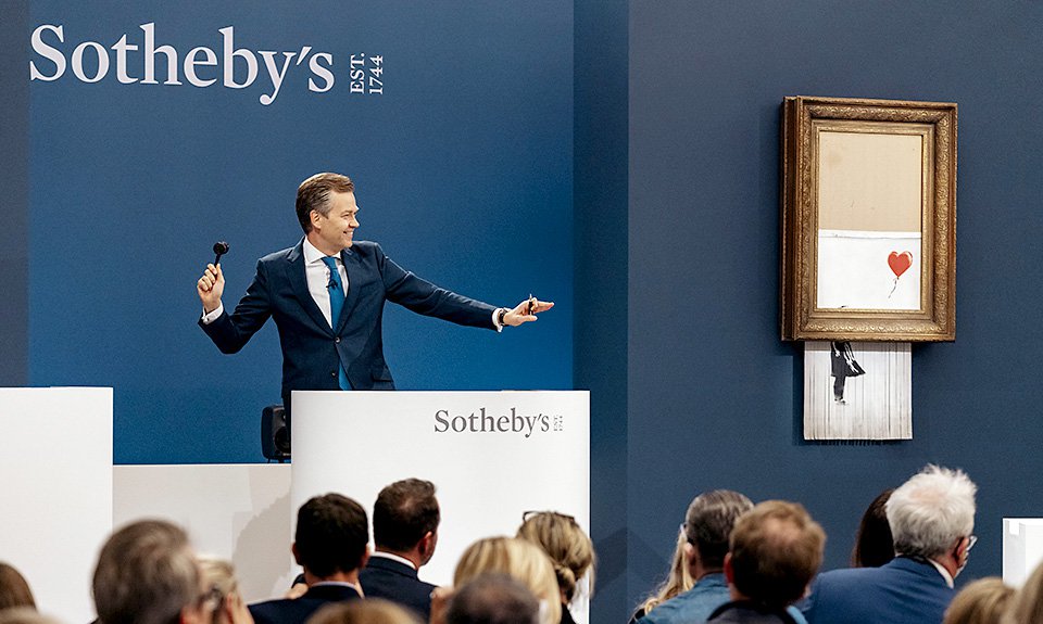 Аукционист Оливер Баркер принимает ставки на «Любовь в мусорном ведре» Бэнкси. Фото: Sotheby's