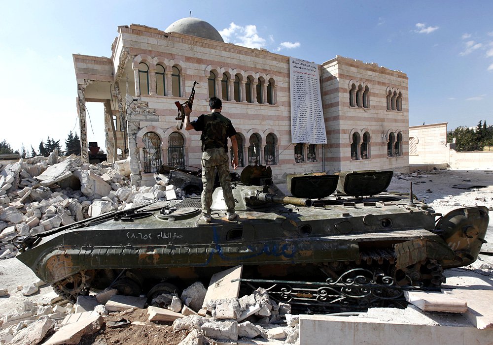 Повстанец на фоне мечети, пострадавшей от боев. Азаз близ Алеппо. Фото: AP Photo/Hussein Malla/Eastnew