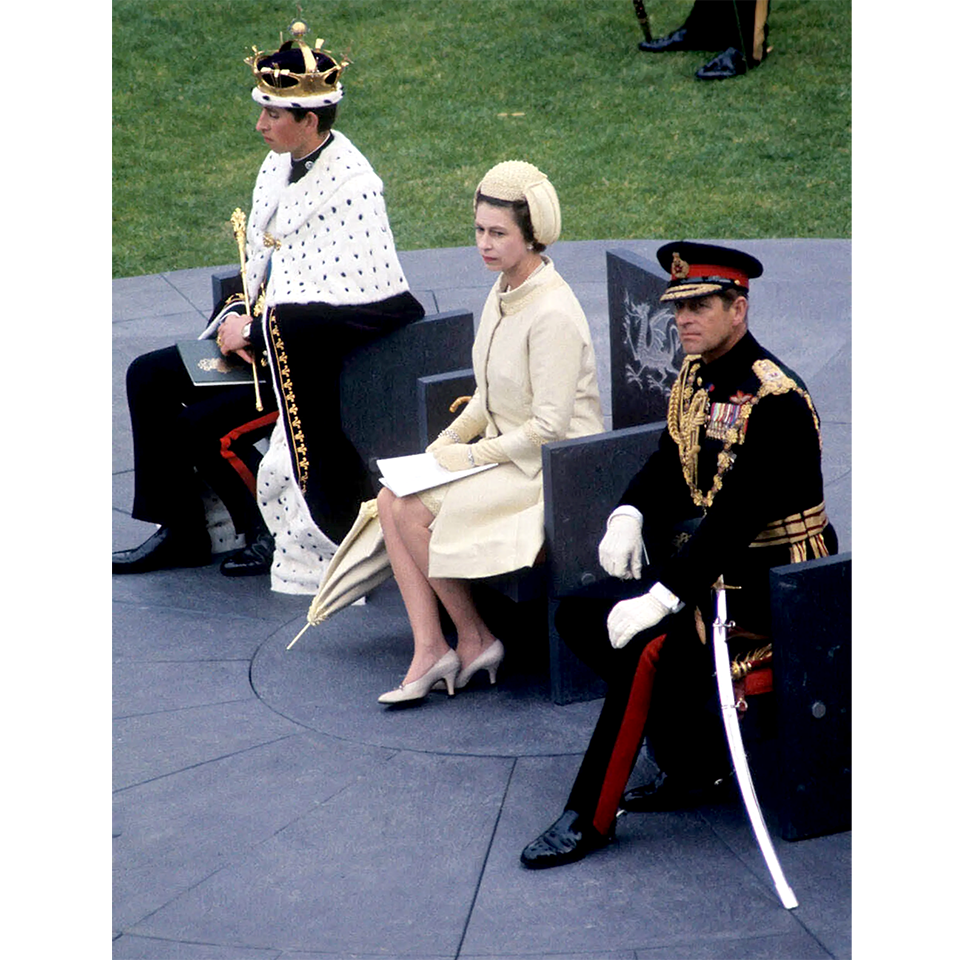 На церемонии инвеституры Чарльза в принцы Уэльские 1 июля 1969 года королева была одета в платье и пальто одного цвета. Шляпка имитировала формы средневекового шлема, намекая на древнюю честь, но при этом ее небольшой размер позволял видеть лицо Елизаветы. Обязательное приложение в такую погоду — зонтик. Фото: PA Images/Alamy Stock Photo