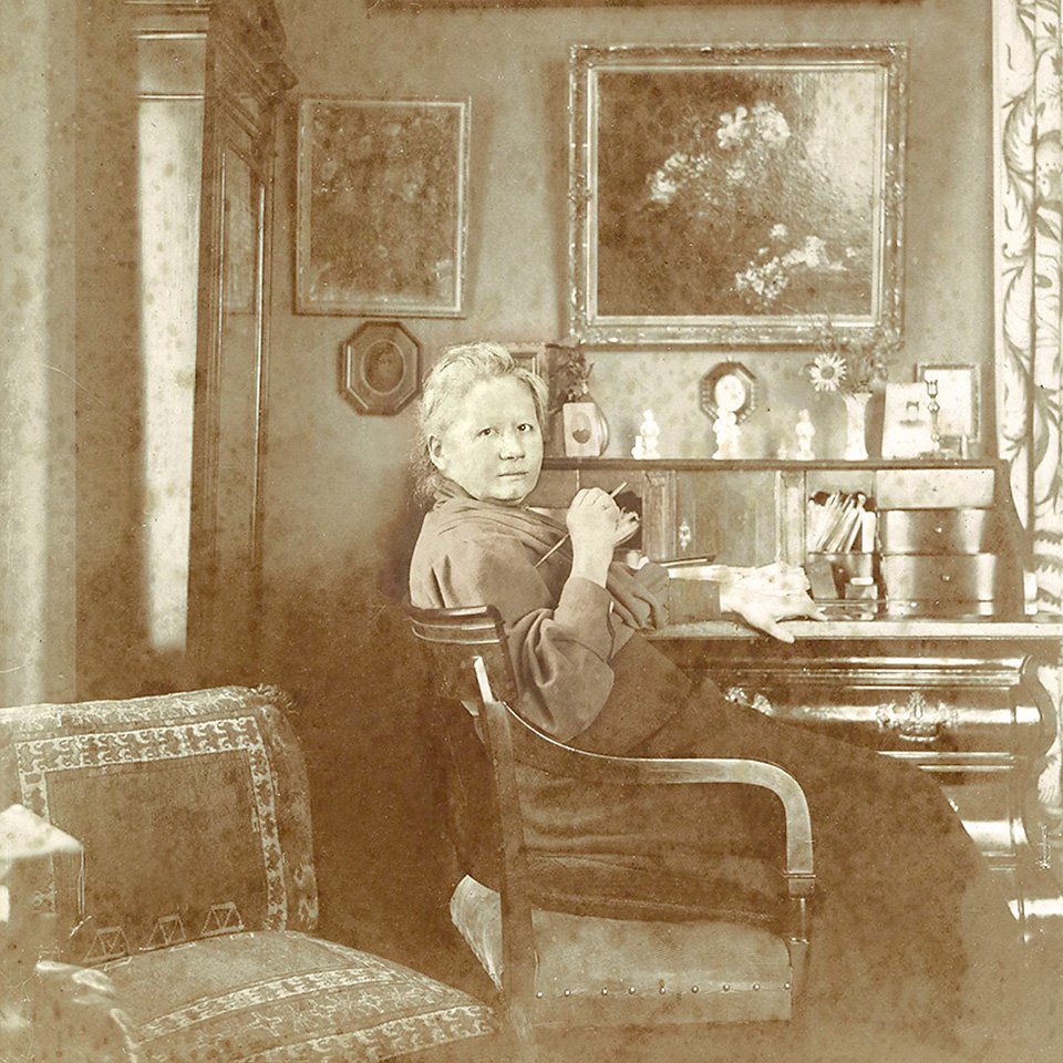 Йоханна ван Гог Бонгер за своим столом в гостиной на Конингинневег, 77 в Амстердаме (1909 или позже). На стене за письменным столом висят картины Фантен-Латура и Винсента ван Гога. Фото: Van Gogh Museum