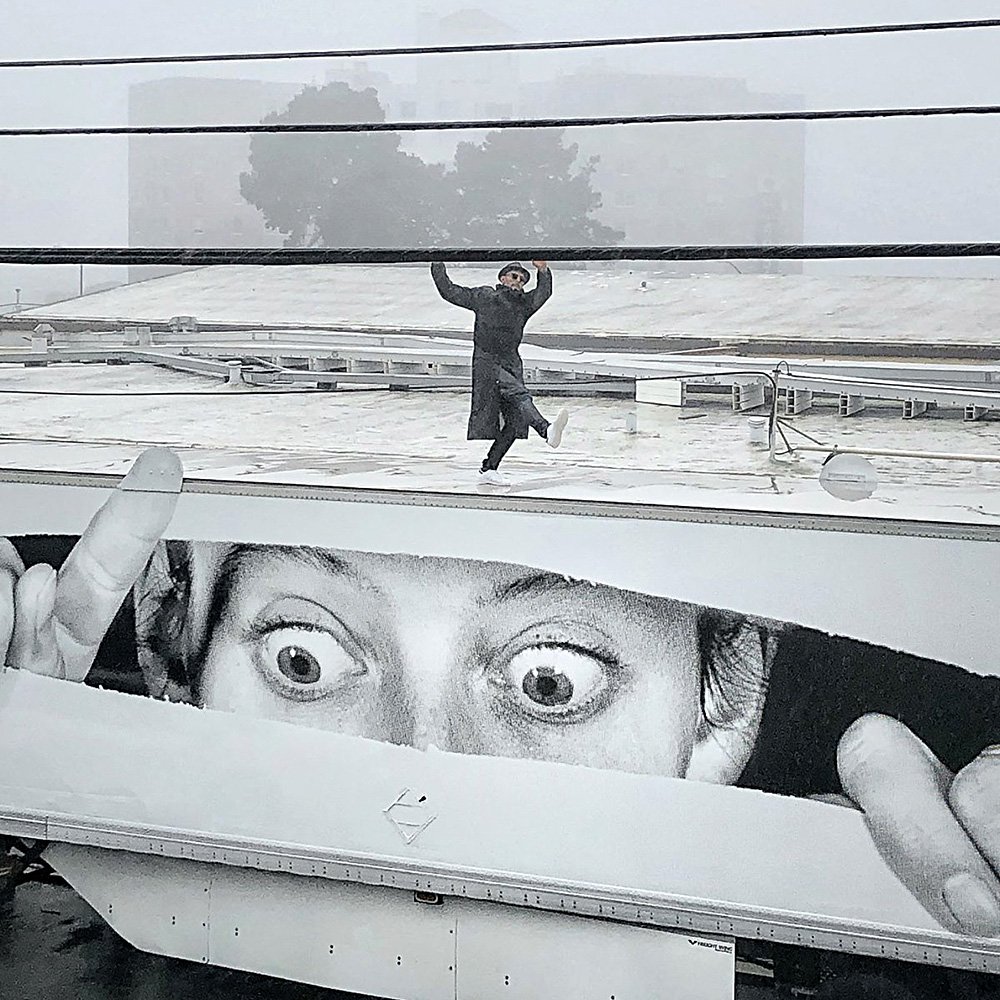 Уличный художник JR на фоне одной из своих работ. Фото: jr-art.net