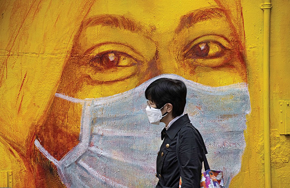 Женщина в защитной маске идет вдоль стены с граффити в Гонконге, Китай. Фото: Miguel Candela Poblacion / Anadolu Agency/ABACAPRESS.COM/Eastnew