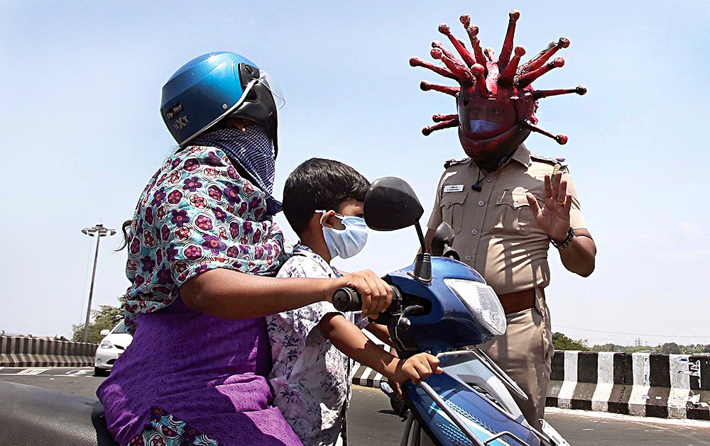 Офицер полиции индийского города Ченнай Раджеш Бабу в шлеме, представляющем собой увеличенную копию вирусной частицы COVID-19. Фото: AP Photo/R. Parthibhan/ТАСС